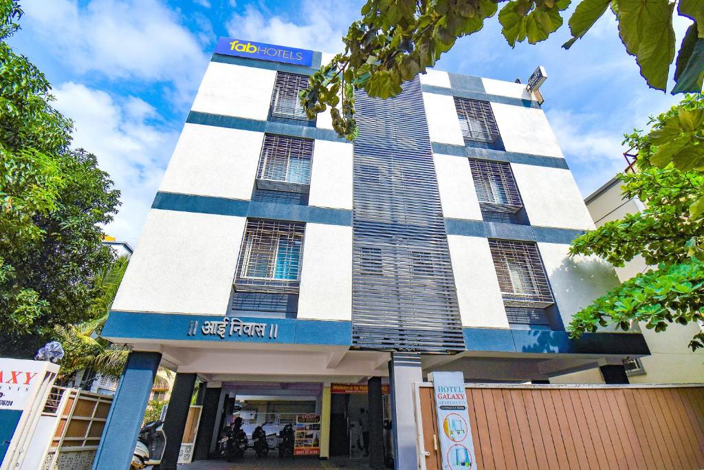 浦那FabExpress Galaxy Apartments - Lohegaon chowk的一座高大的建筑,上面有蓝色和白色的条纹