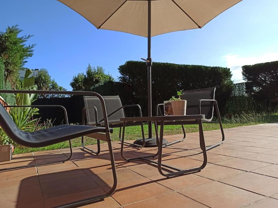 una mesa, sillas y una sombrilla en el patio en Bajo con jardín privado, en Santander