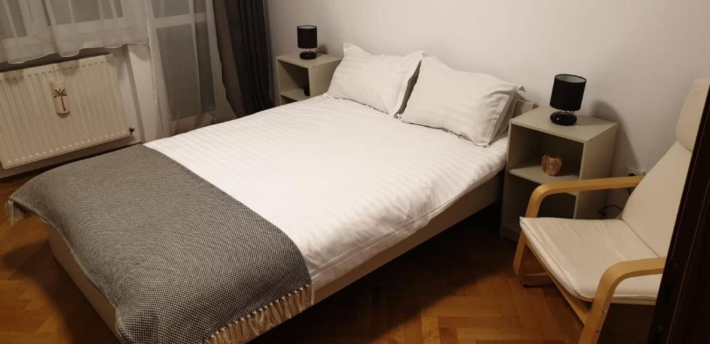a bedroom with a white bed and a chair at Zinne Centru Civic in Braşov