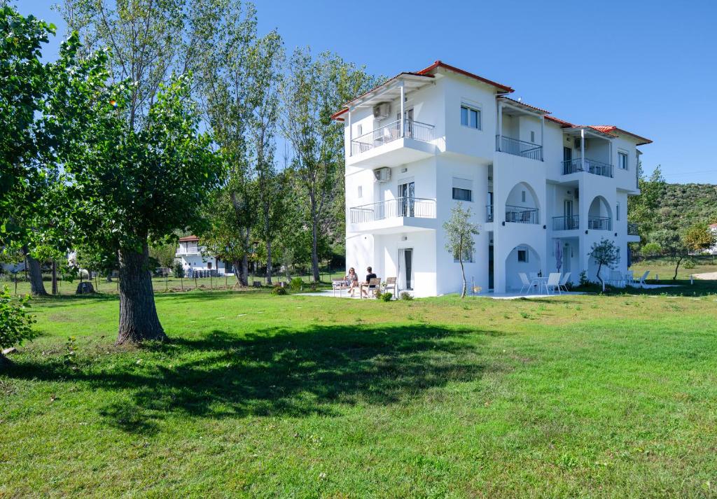 une grande maison blanche avec un arbre dans un champ dans l'établissement Grand Garden Slow Living Experience, à Sikia