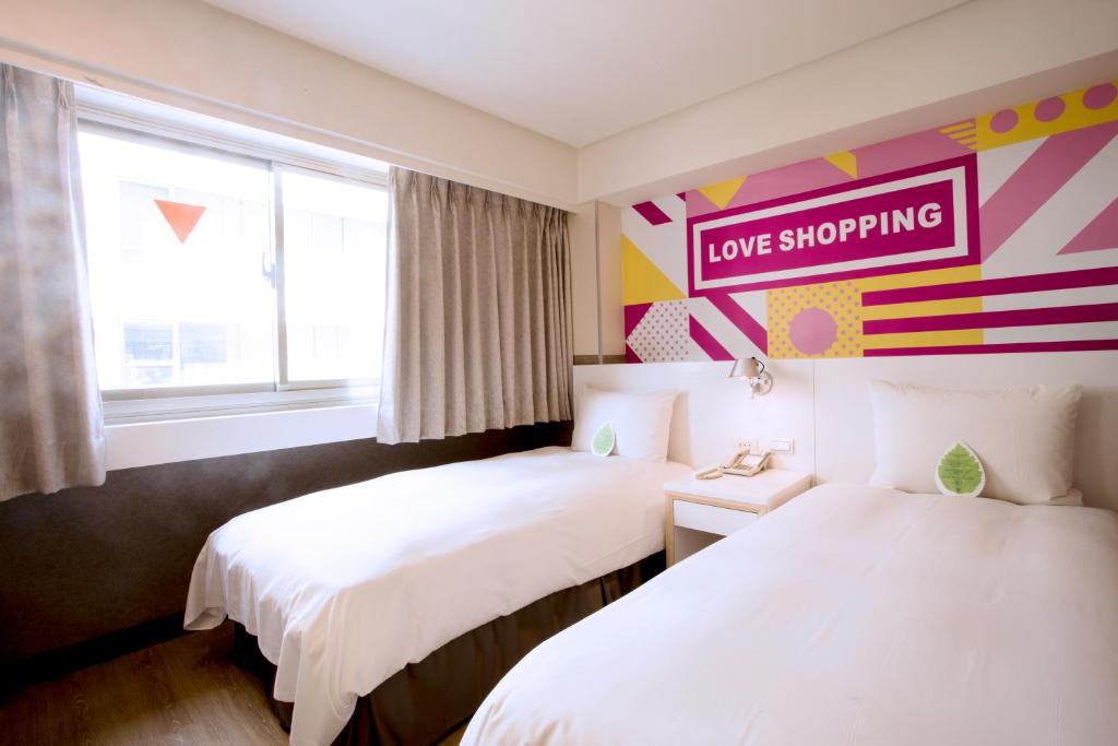 two beds in a room with a love shopping sign on the wall at Ximen Citizen Hotel in Taipei