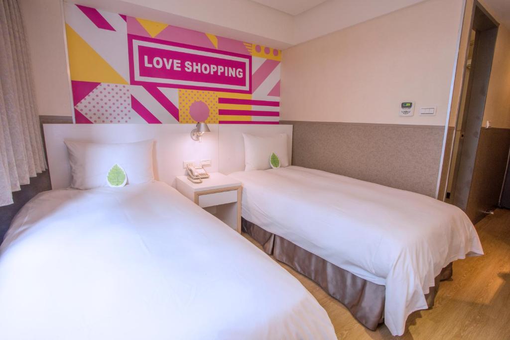 two beds in a room with a love shopping sign on the wall at Ximen Citizen Hotel in Taipei