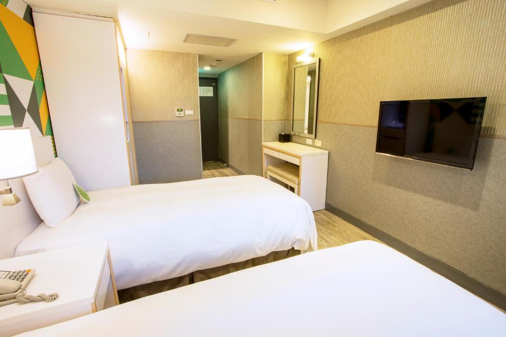 a hotel room with two beds and a flat screen tv at Ximen Citizen Hotel in Taipei