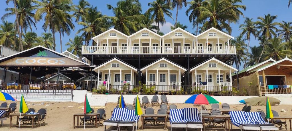 a building on the beach with chairs and umbrellas at Cocos Beach Resort in Palolem