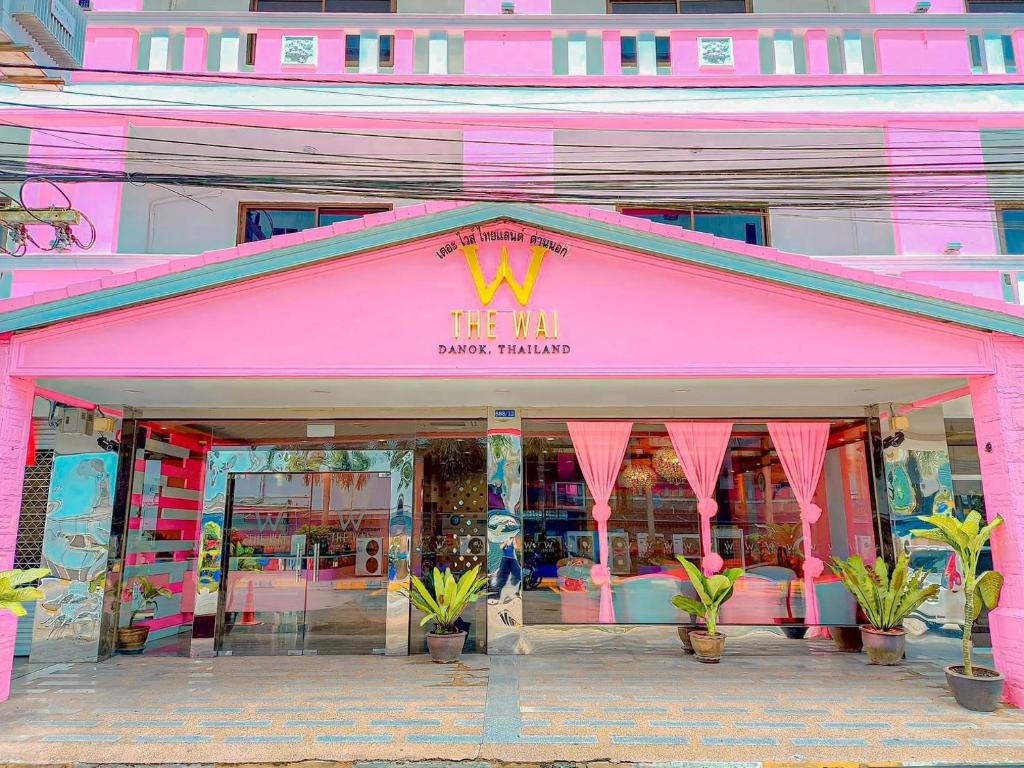 een roze winkel met planten ervoor bij The Wai Hotel Danok in Sadao