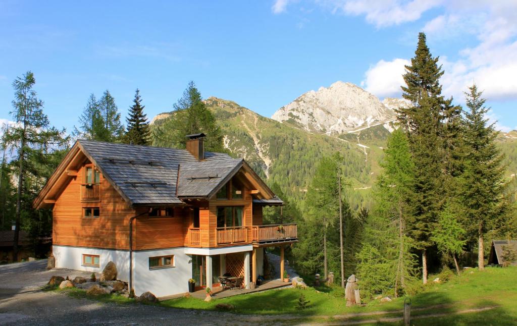 eine Blockhütte in den Bergen mit einem Berg in der Unterkunft Almhaus Nassfeld in Sonnenalpe Nassfeld