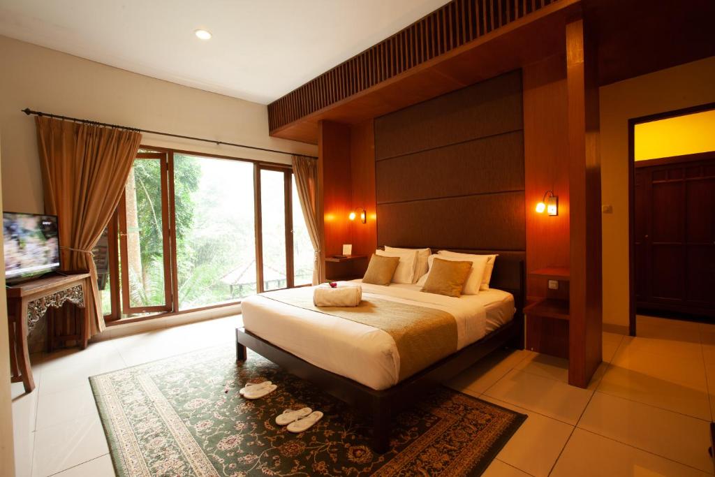 a bedroom with a large bed and a large window at Villa Puncak by Plataran in Puncak