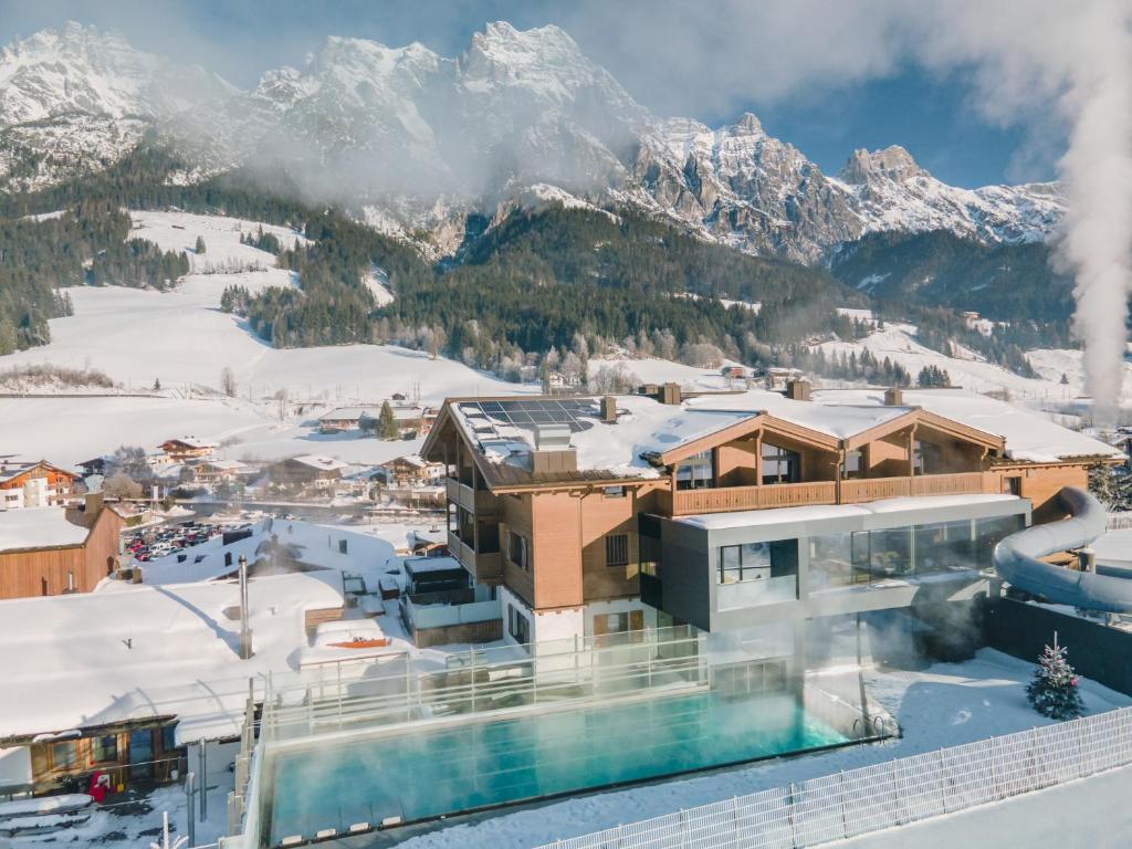 a resort in the snow with mountains in the background at Hotel Riederalm in Leogang