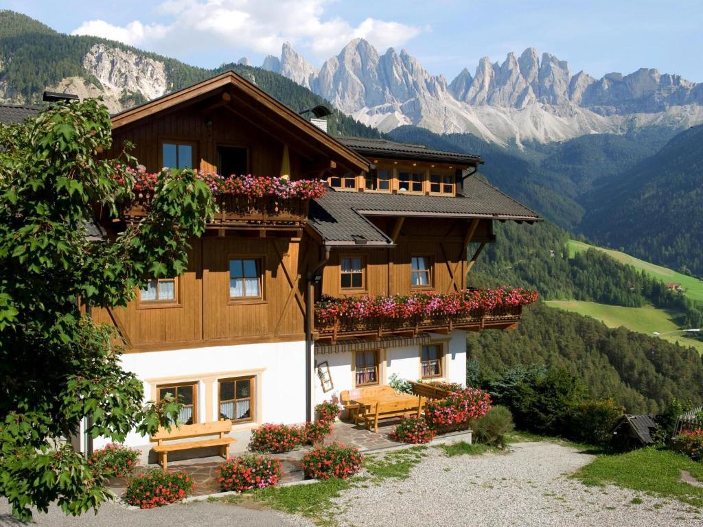 a house in the mountains with flowers on the balconies at Apartments home Niedermunthof, Villnöß in Funes