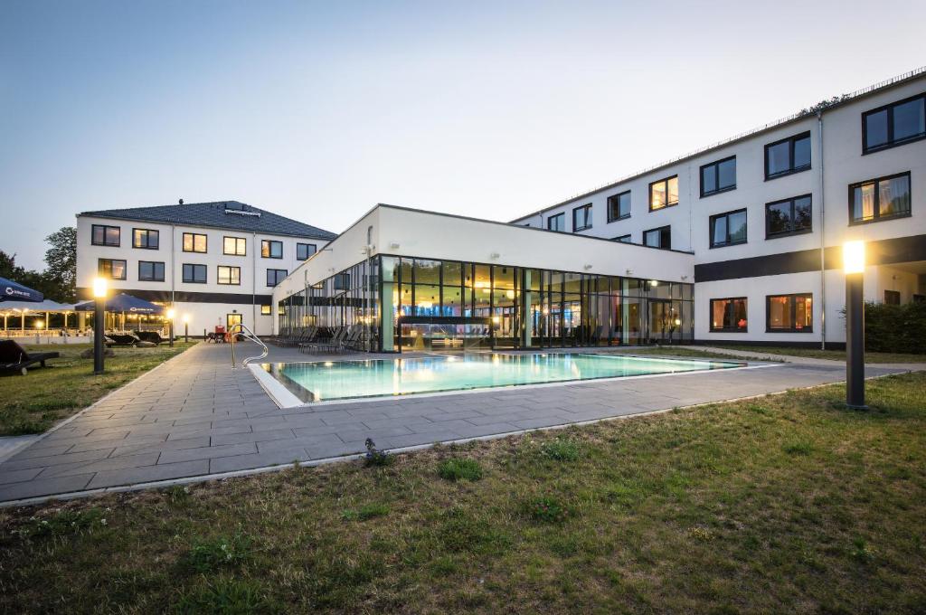 un bâtiment avec une piscine en face d'un bâtiment dans l'établissement aja Bad Saarow, à Bad Saarow