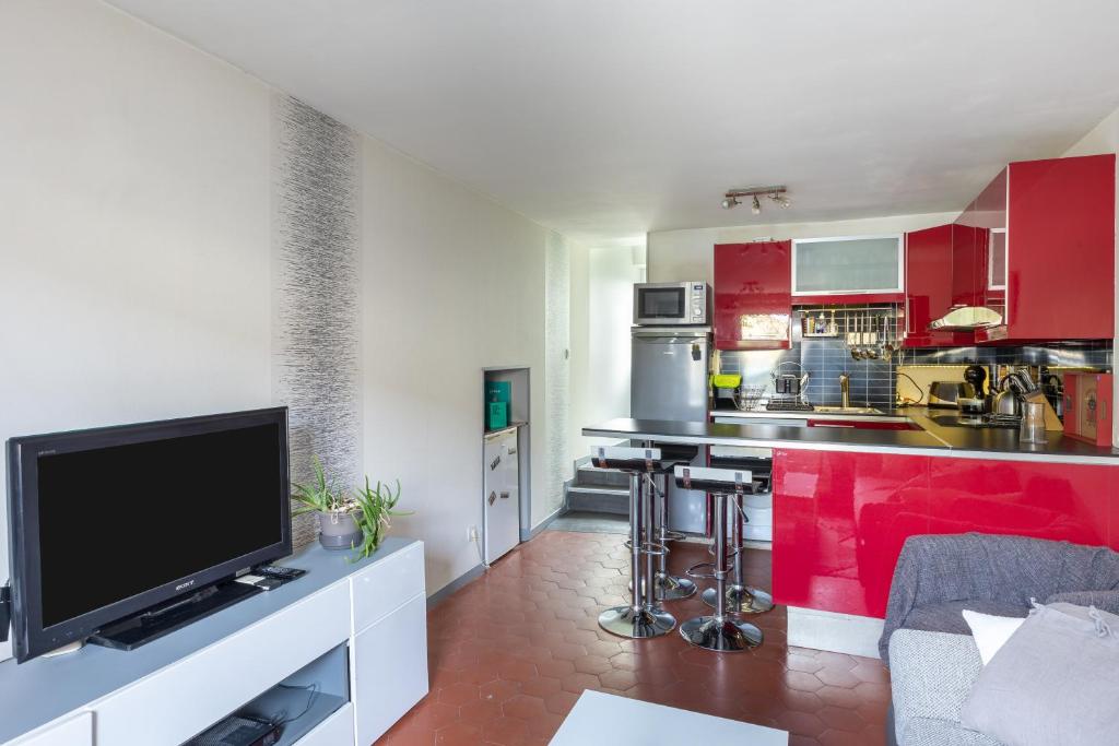 una cocina con armarios rojos y TV. en Maison Mareuil, en Mareuil-lès-Meaux