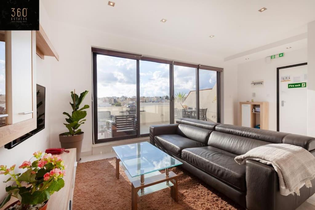 ein Wohnzimmer mit einem Ledersofa und einem Glastisch in der Unterkunft Penthouse with BBQ Kitchen Island & Massive Living room by 360 Estates in St Julian's