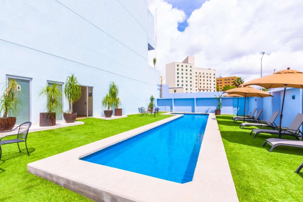 普埃布拉的住宿－NH Puebla FINSA，大楼内一个带椅子和遮阳伞的游泳池