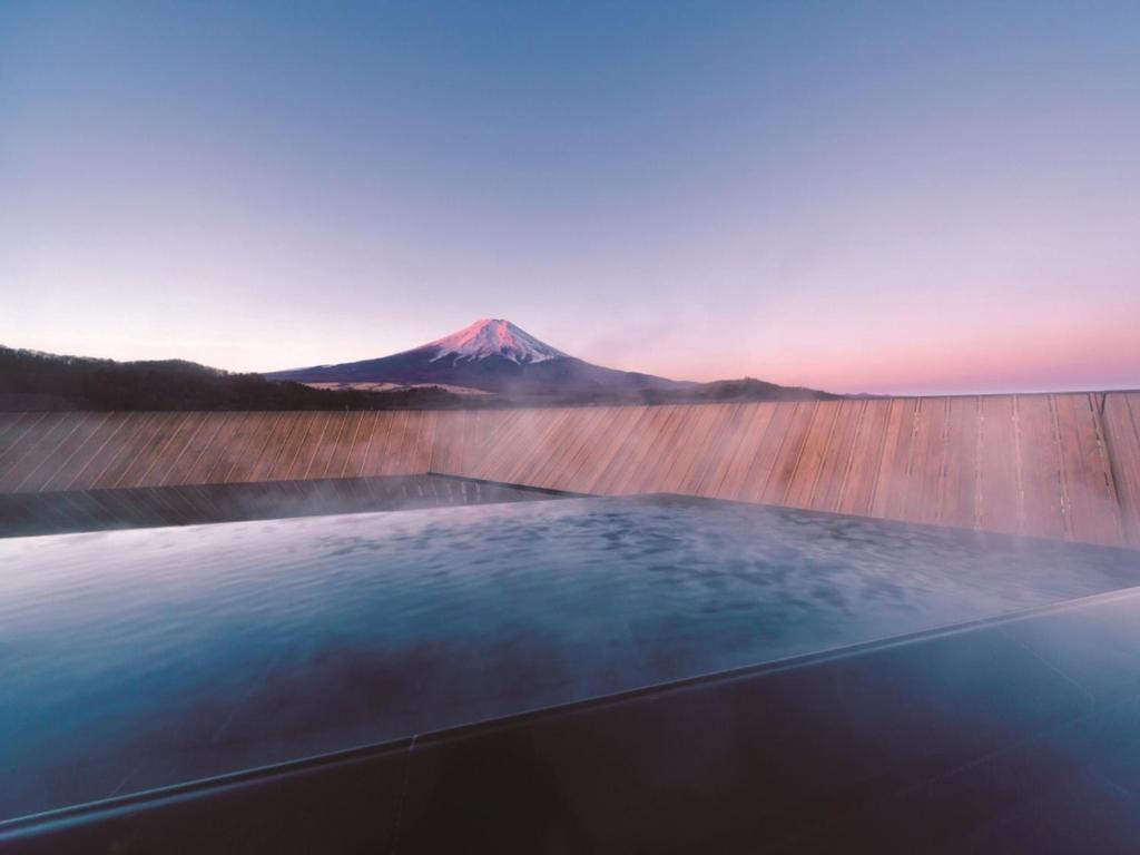 a mountain in the distance with a hot tub at Kaneyamaen in Fujiyoshida