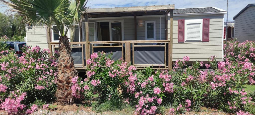 una casa con flores rosas delante de ella en Mobil Home Palmiers 1, en Valras-Plage