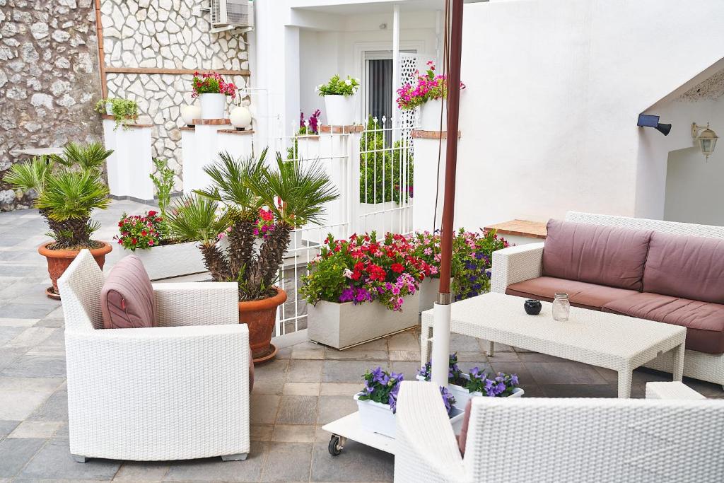 a patio with white chairs and potted plants at B&B Casa Silvana in Capri