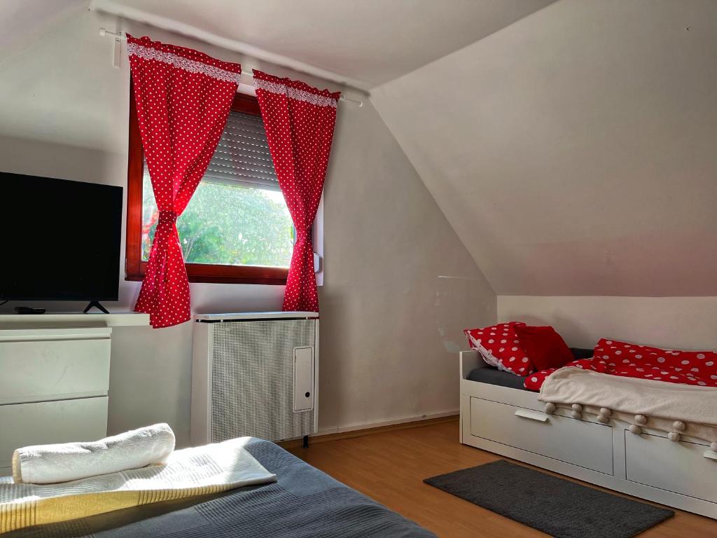 a bedroom with a bed and a window with red curtains at PöttyösOtthon Vendégház in Tiszabábolna