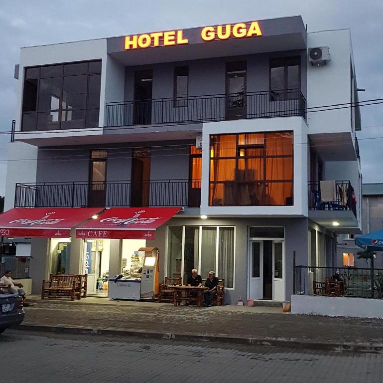 a hotel with two people sitting in front of it at HOTEL GUGA in Kobuleti