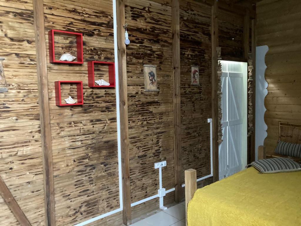 a bedroom with a wooden wall with red frames at Yeux D&#39;azur in Le Souffleur