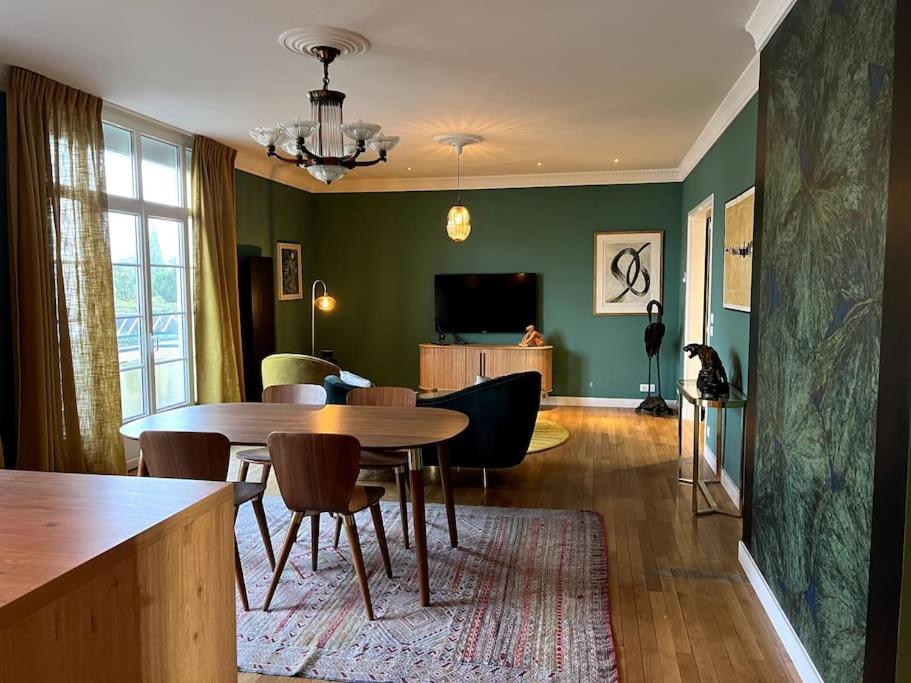 uma sala de estar com uma mesa e cadeiras e uma televisão em St Nazaire Jardin des plantes superbe appartement em Saint-Nazaire