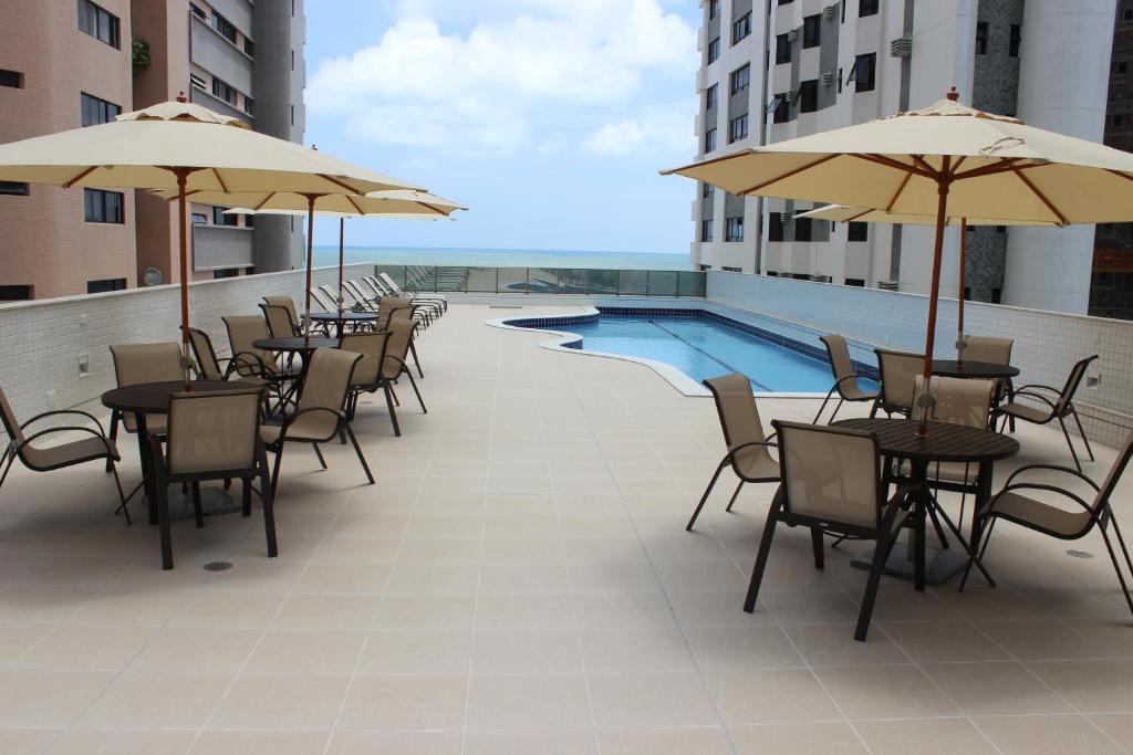 un patio con mesas y sillas y una piscina en Flat Beach Class Executive, en Recife
