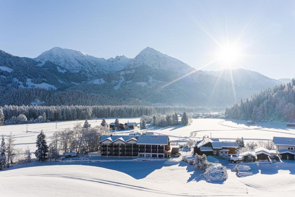 a ski lodge in the snow with mountains in the background at Wohlfühlhotel Frohsinn in Fischen