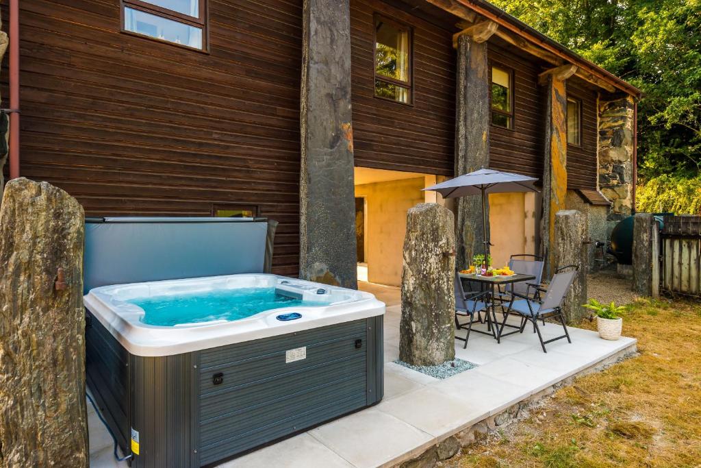a hot tub on a patio next to a house at Finest Retreats - Idris Barn Helm y Llwyn Barn in Dolgellau