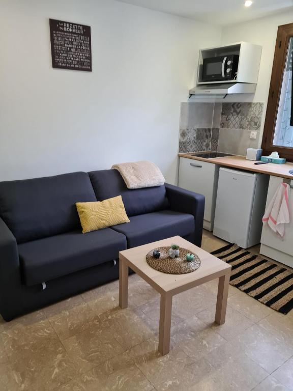un salon avec un canapé bleu et une table basse dans l'établissement Studio bien équipé et indépendant avec véranda commune, à Neuilly-sur-Marne