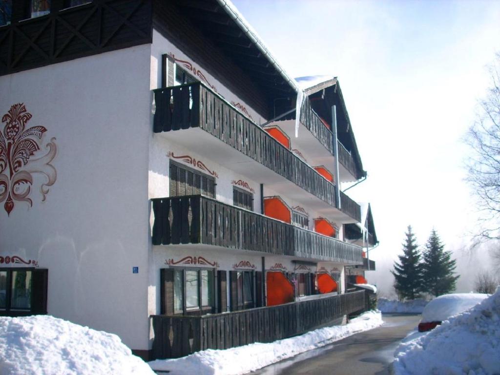 ein weißes Gebäude mit Balkonen und Schnee auf dem Boden in der Unterkunft Ferienwohnung Hani in Spiegelau
