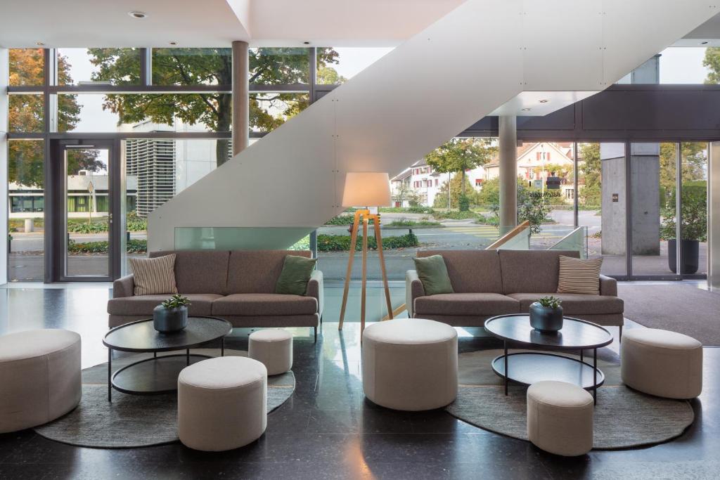 a lobby with couches and tables in a building at Hotel Baslertor in Muttenz