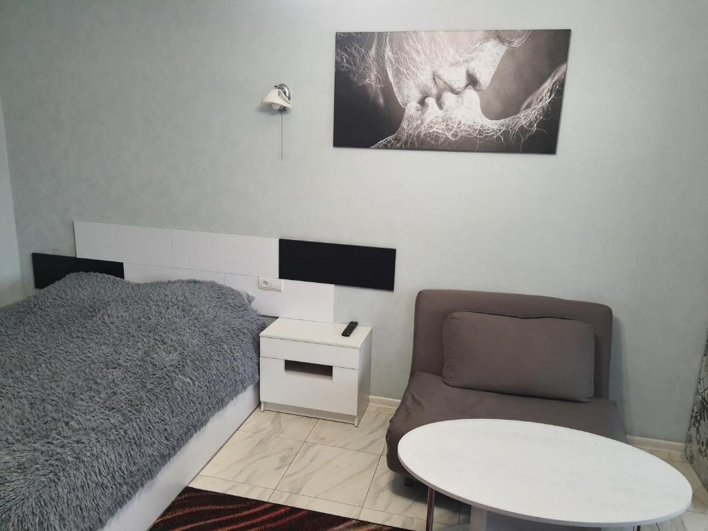 a bedroom with a bed and a chair and a table at Apartment on Mstyslavs'ka in Chernihiv