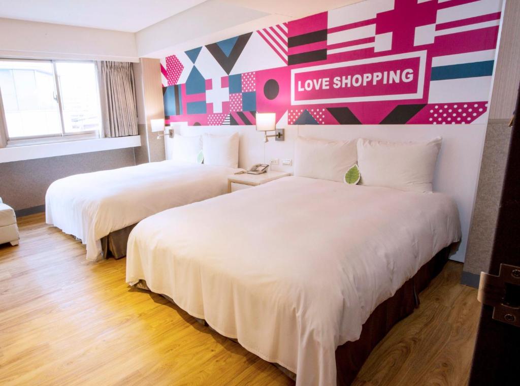 a hotel room with two beds and a love shopping sign on the wall at Ximen Citizen Hotel in Taipei