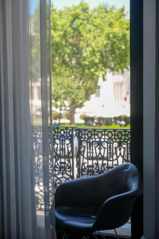 a chair sitting on a balcony looking out a window at RM The Experience - Small Portuguese Hotels in Setúbal