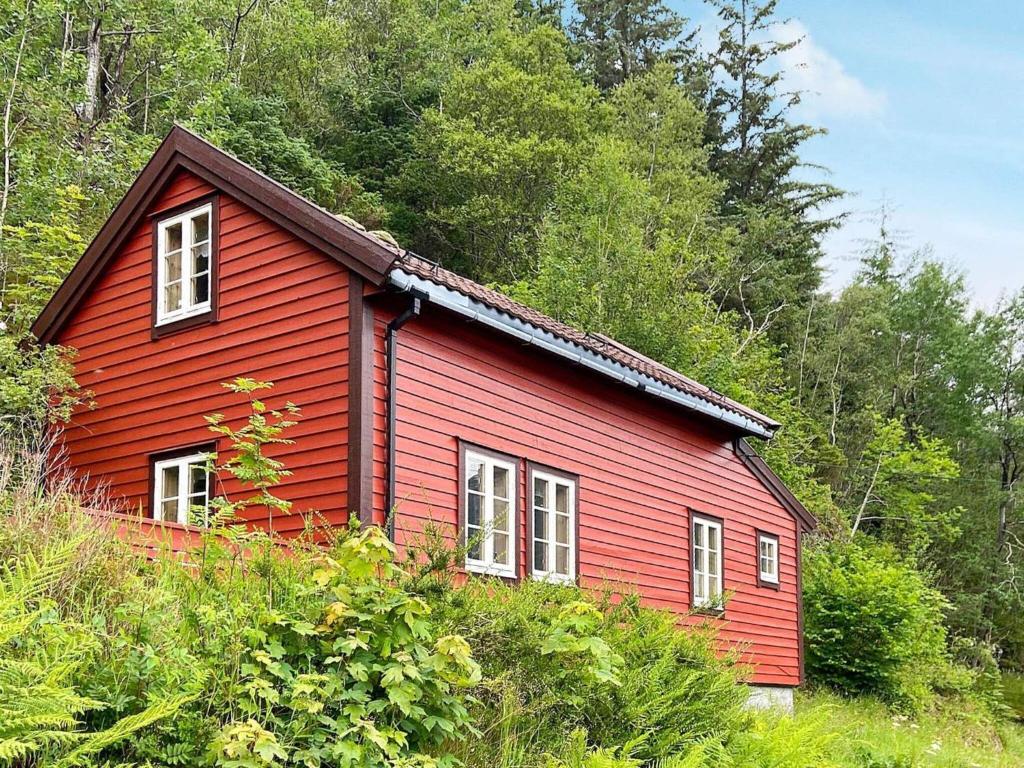 una casa roja en medio de un bosque en Holiday home HARDBAKKE II, en Hardbakke