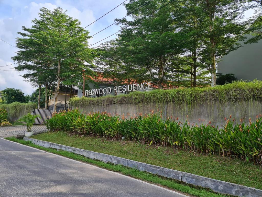 a sign on a retaining wall next to a street at Redwood Residence in Pangkalpinang