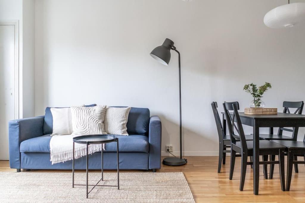 uma sala de estar com um sofá azul e uma mesa em 1br apartment with patio in Lauttasaari em Helsinque