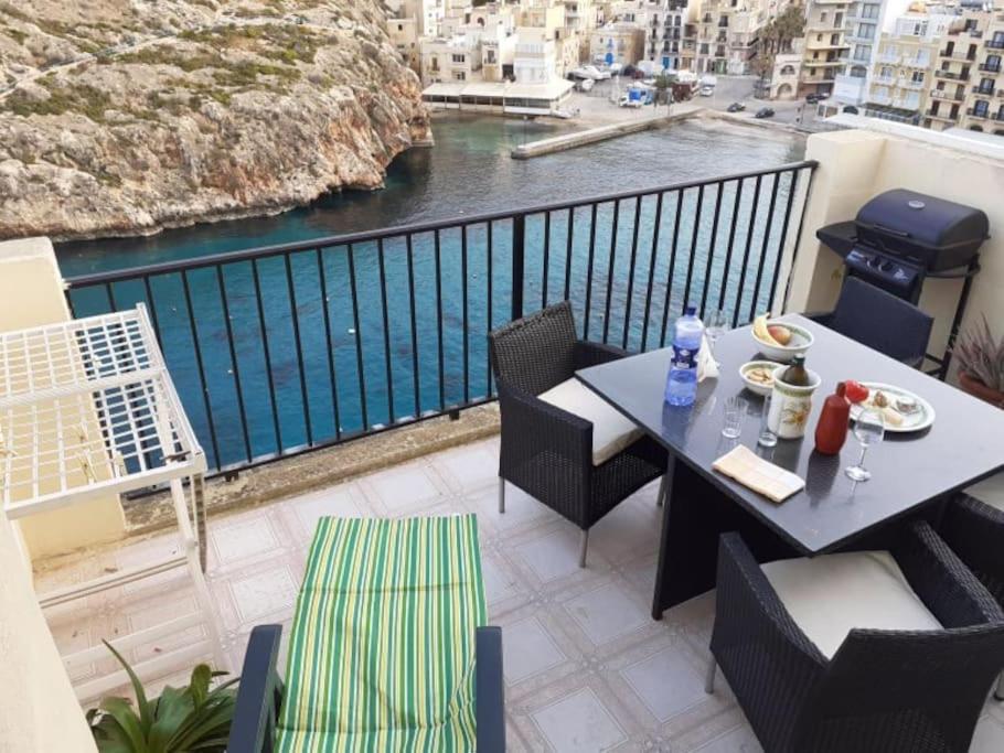 una mesa y sillas en un balcón con vistas al agua en Seafront Penthouse with Terrace in Xlendi, Gozo, en Xlendi