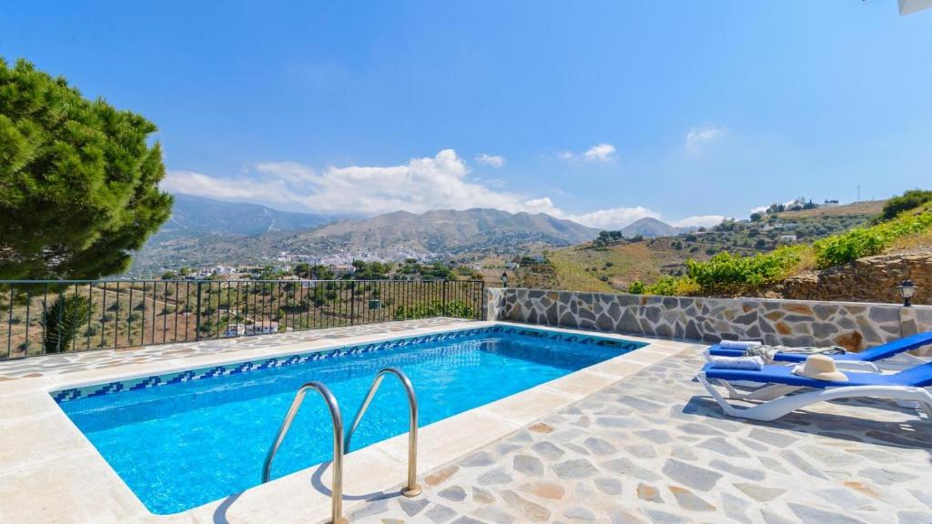 una piscina con 2 sillas y vistas a las montañas en Finca Los Pinos Cómpeta by Ruralidays, en Cómpeta