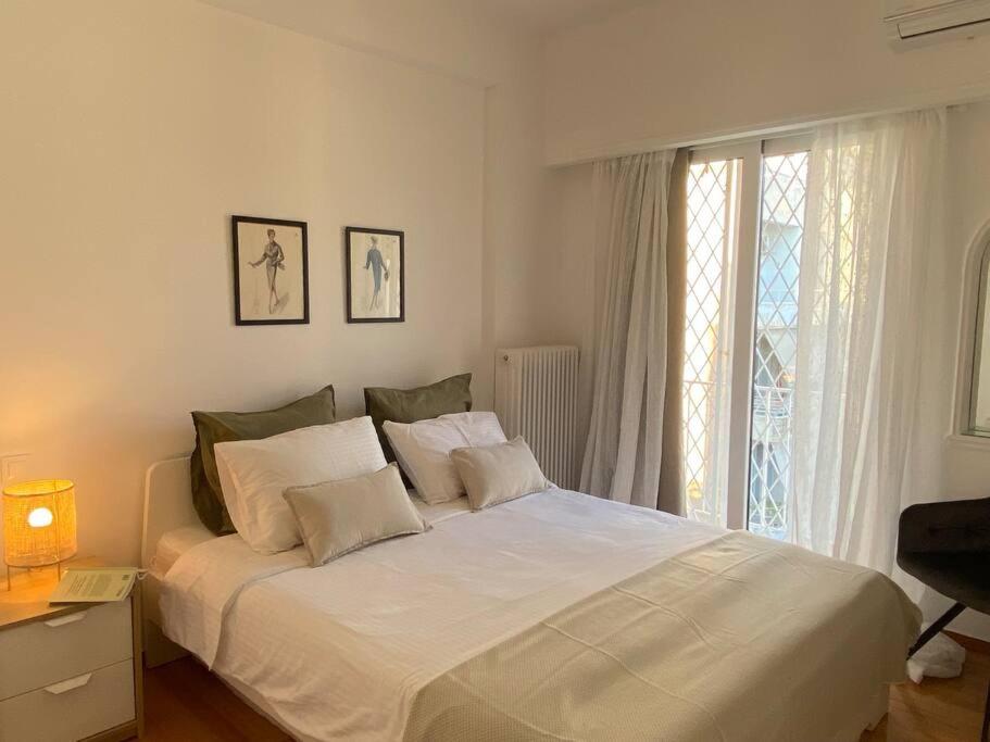un letto bianco in una camera da letto con finestra di Kolonaki 1 bedroom and 1 Sofabed Amazing Penthouse flat ad Atene