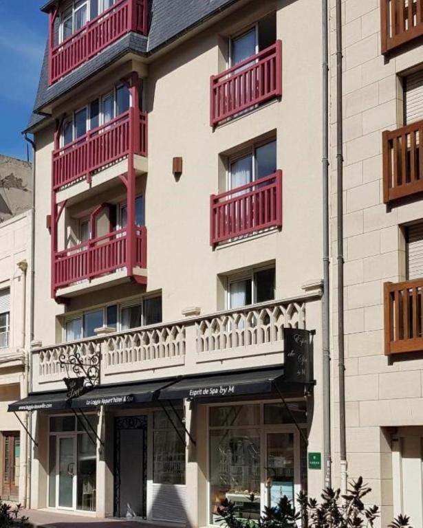 a building with red balconies on the side of it at La Loggia Appart'Hôtel & Spa in Deauville