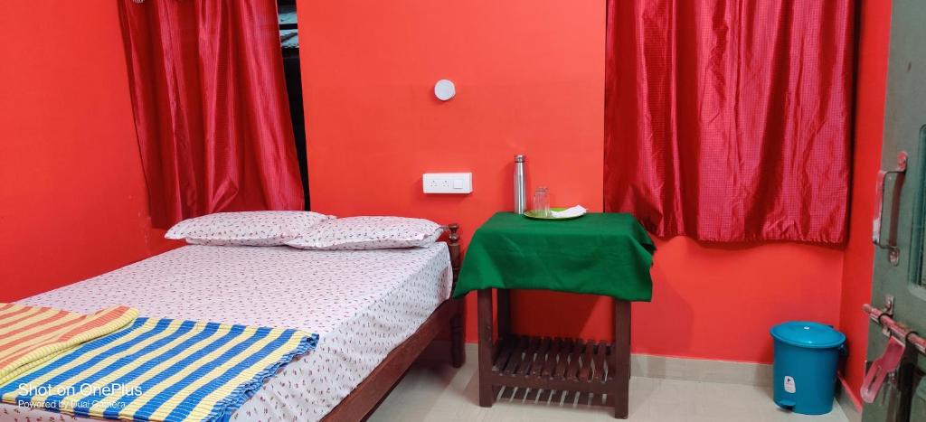 a bedroom with red walls and a bed and a table at Sajeev Home Stay in Cherai Beach