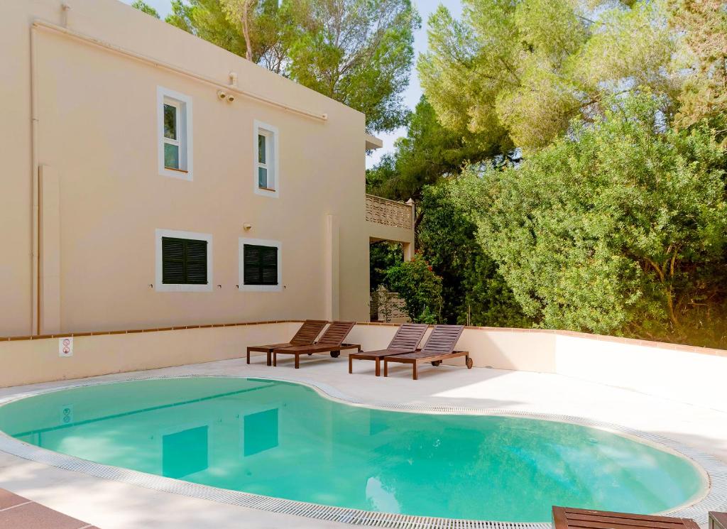 una piscina con due sedie e una casa di Apartamentos El Pino - Formentera Break a Es Caló de Sant Agustí
