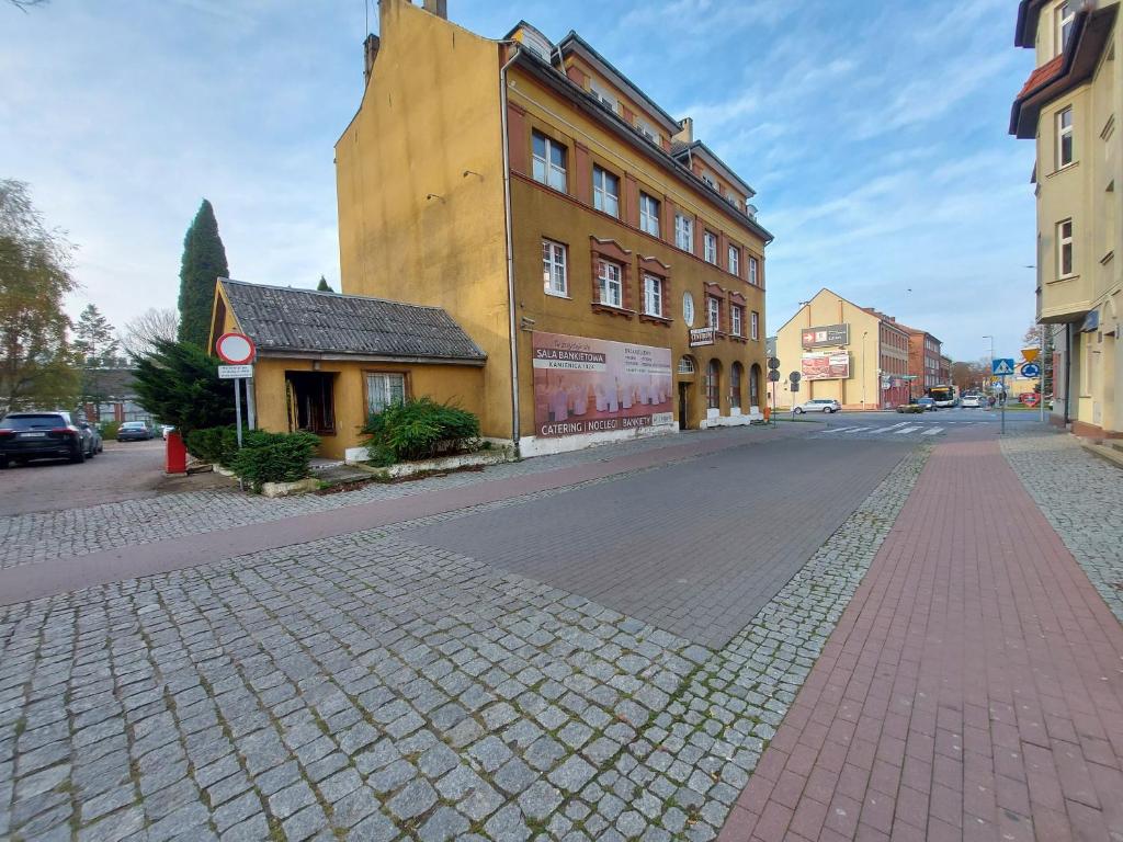uma rua de paralelepípedos numa cidade com um edifício em Kamienica1924 em Szczecinek