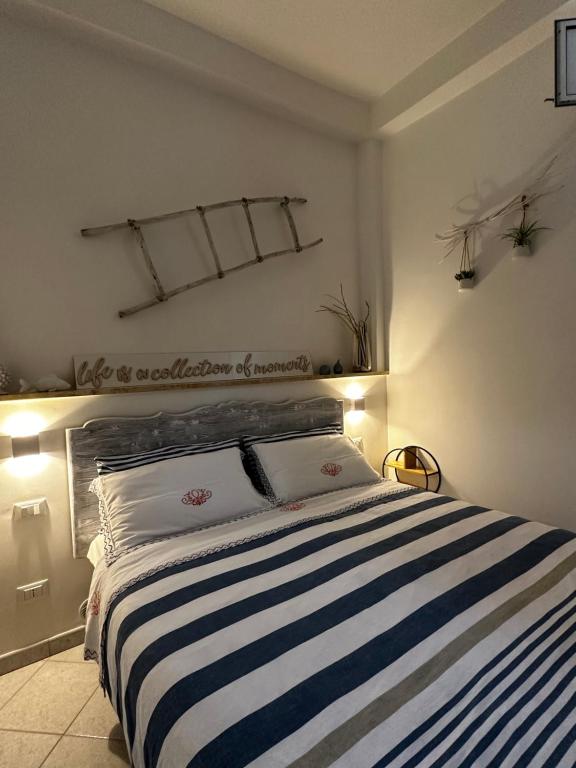 een slaapkamer met een bed met een blauw en wit gestreepte deken bij White House in Torre Canne