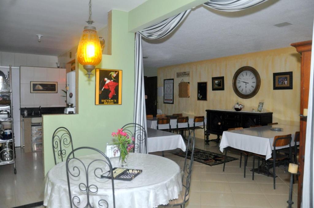 um restaurante com mesas e cadeiras e um relógio na parede em ANGEL'S SEA Pousada em Rio das Ostras