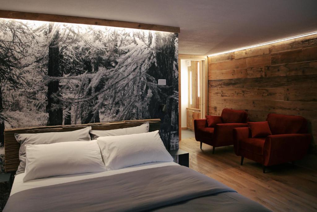 a bedroom with a large bed and two chairs at Maison Farinet in Saint-Rhémy-en-bosses