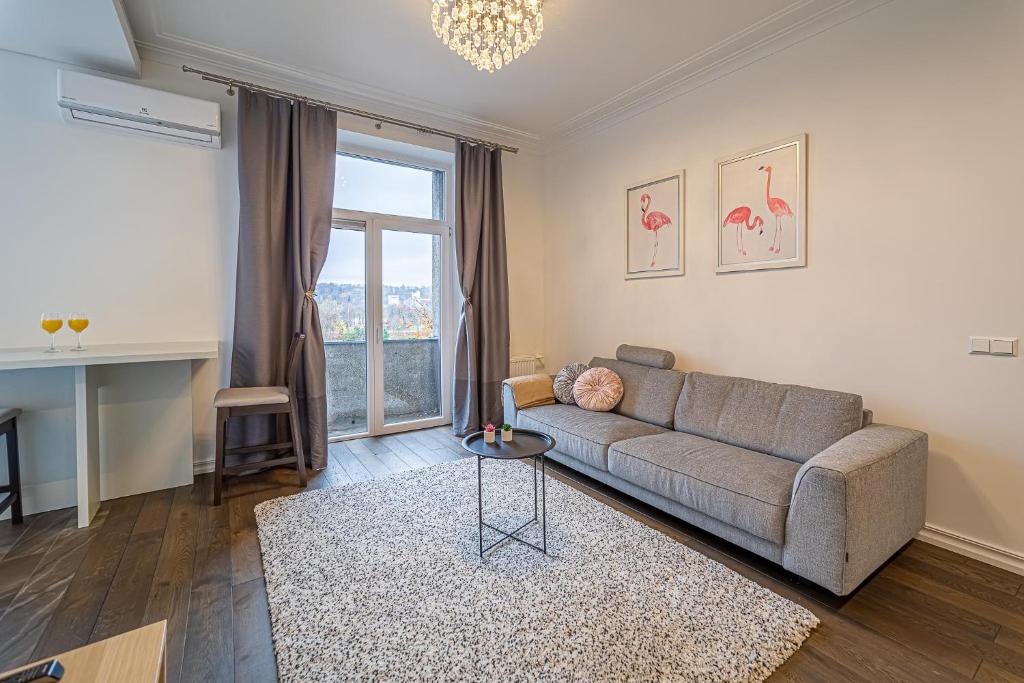 a living room with a couch and a large window at Žalgiris arena apartment with AC in Kaunas