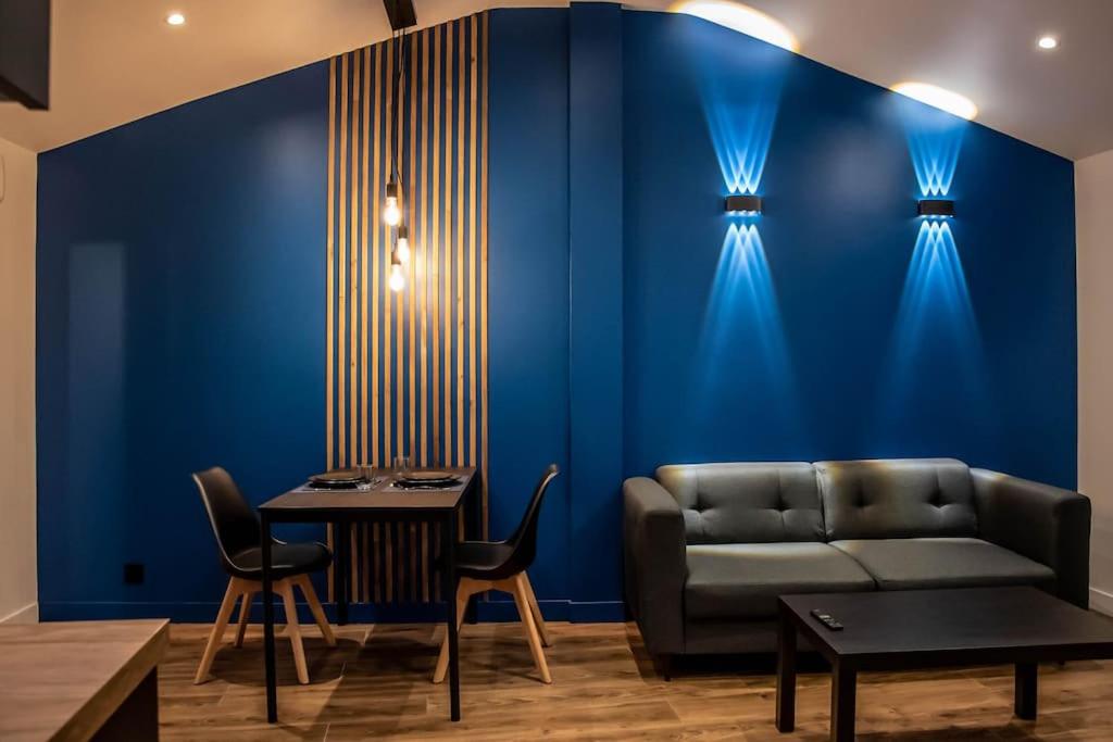 a living room with a couch and a blue wall at BLUE NIGHT - Jacuzzi - Bord de Seine in Corbeil-Essonnes