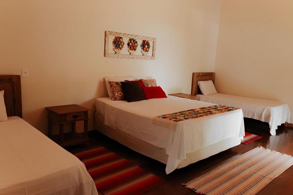 a bedroom with two beds and a rug at Hotel Pousada Chalé das Flores in Sertãozinho