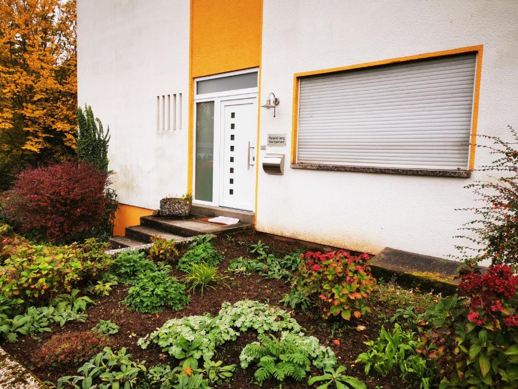 een huis met een deur en een bloementuin bij Dagmars Apartment in Steinwenden